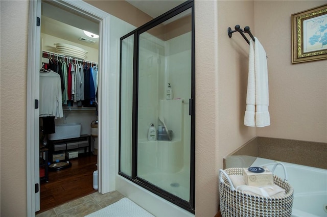 full bathroom featuring a stall shower, a garden tub, a spacious closet, and tile patterned floors