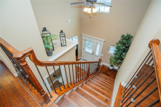 staircase featuring wood finished floors, a ceiling fan, and baseboards