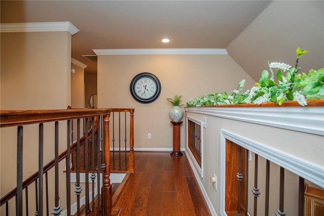 hall with dark wood-type flooring, visible vents, ornamental molding, and an upstairs landing