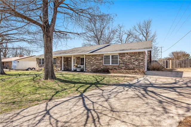 ranch-style house featuring driveway, brick siding, a front yard, and fence