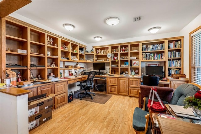 home office featuring visible vents, light wood-style floors, and built in study area