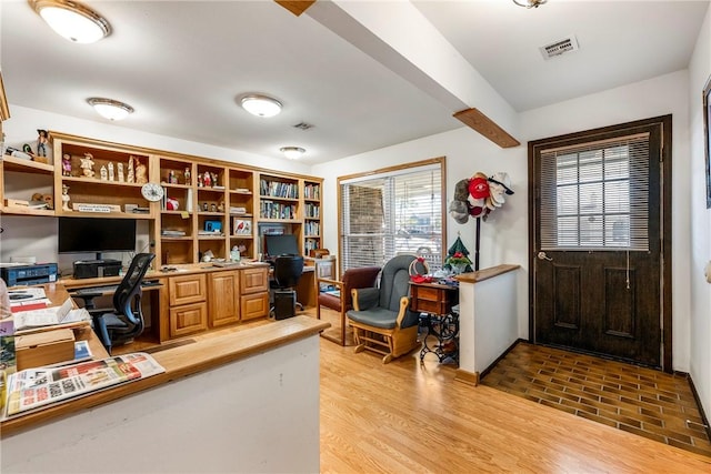 office area featuring beam ceiling, visible vents, light wood-type flooring, and built in study area