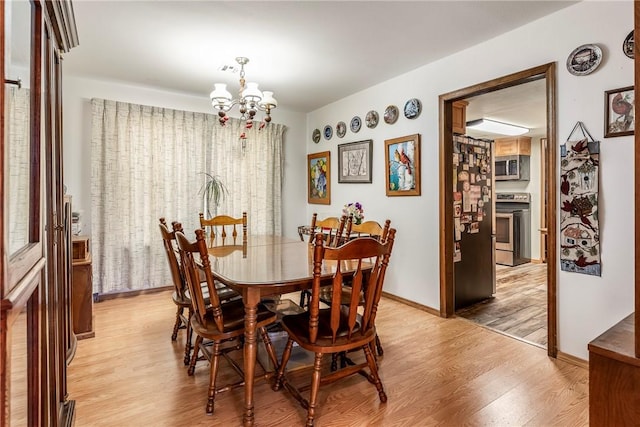 dining area featuring a chandelier, baseboards, and light wood-style floors