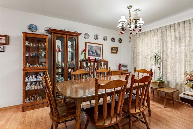 dining room with a chandelier, light wood-type flooring, and baseboards