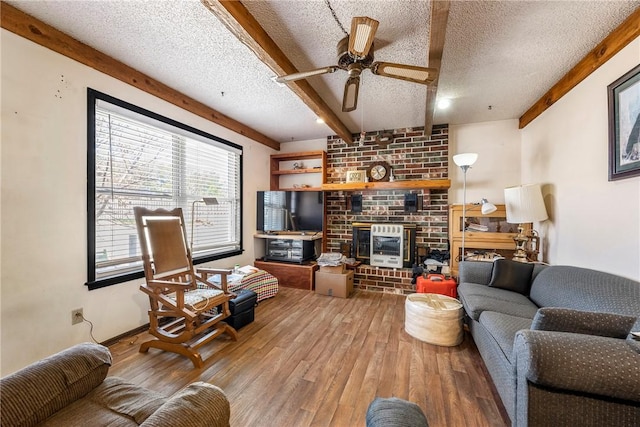 living area with beam ceiling, wood finished floors, and a textured ceiling