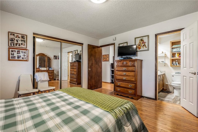 bedroom featuring a closet, a textured ceiling, light wood-style flooring, and ensuite bathroom