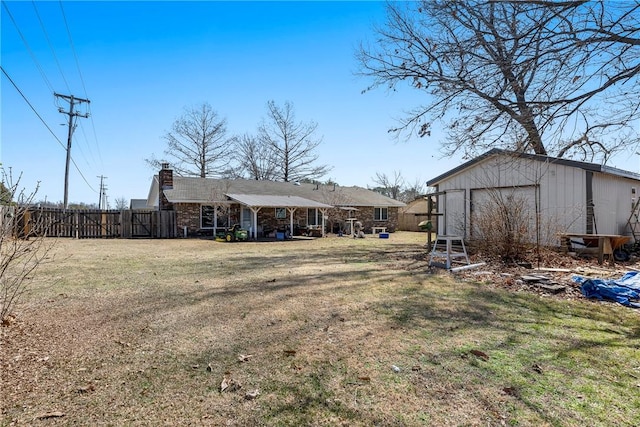 view of yard featuring a detached garage, an outbuilding, and fence