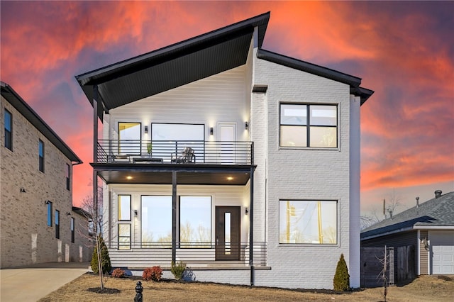 view of front of home with a porch, brick siding, and a balcony