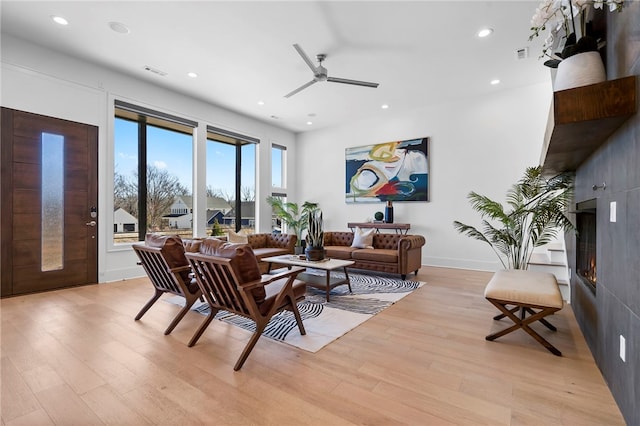 living area featuring visible vents, baseboards, a lit fireplace, light wood-type flooring, and recessed lighting