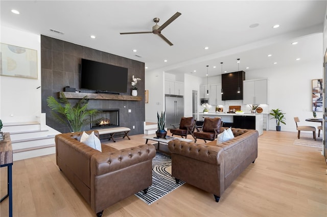 living room with light wood-style floors, recessed lighting, visible vents, and a tiled fireplace