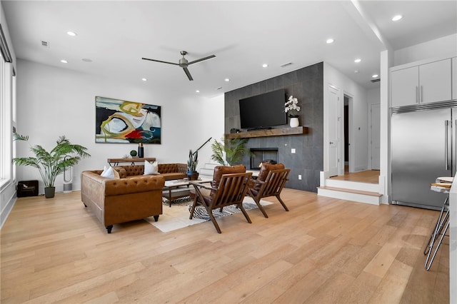 living room featuring visible vents, a tile fireplace, light wood-style flooring, and recessed lighting