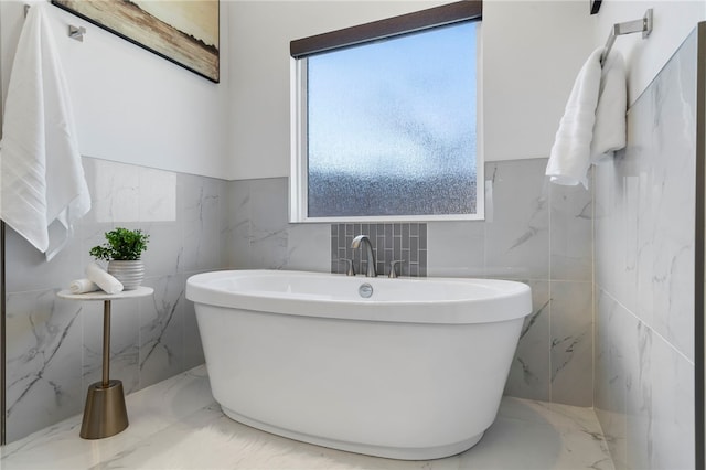 bathroom featuring marble finish floor and a freestanding tub