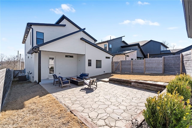 rear view of property with a fire pit, brick siding, a patio area, and a fenced backyard