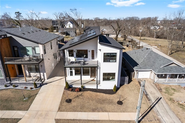 view of front of house featuring fence, a balcony, a garage, a residential view, and driveway