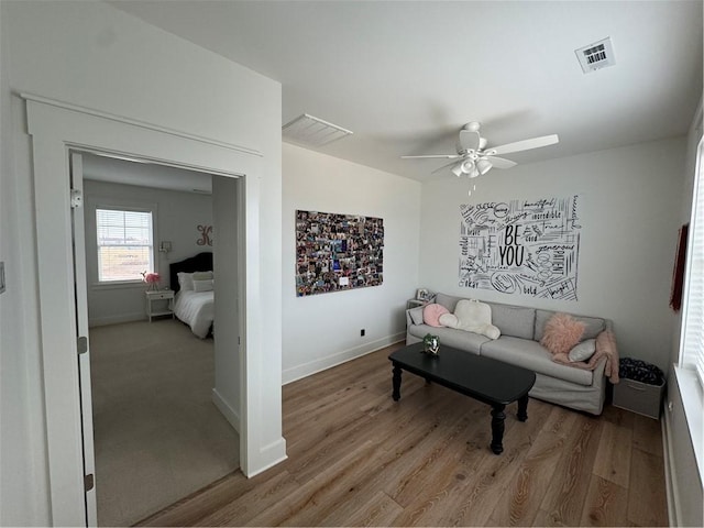 living area with visible vents, ceiling fan, light wood-style flooring, and baseboards