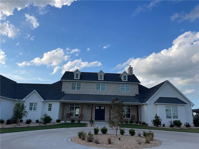 view of front of house with a standing seam roof, curved driveway, metal roof, and covered porch