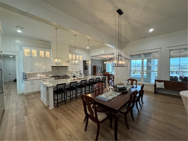 dining room with a chandelier, ornamental molding, wood finished floors, and recessed lighting