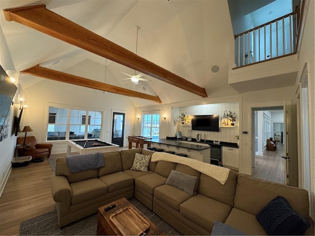 living room featuring beam ceiling, a ceiling fan, wood finished floors, high vaulted ceiling, and baseboards