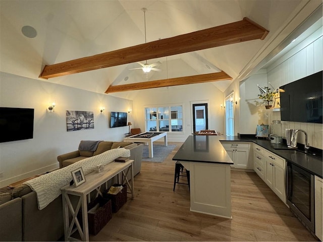 kitchen featuring light wood-style floors, dark countertops, open floor plan, and a sink