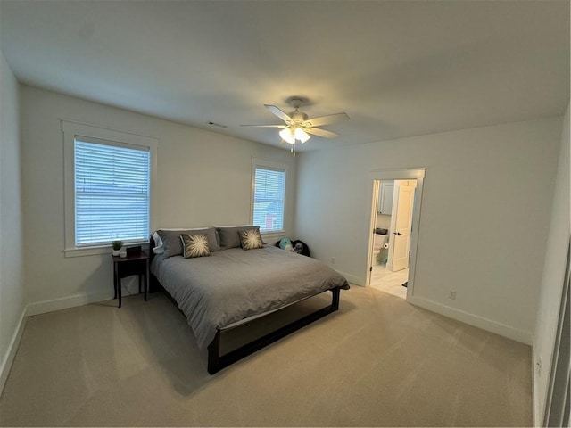 bedroom with light carpet, ceiling fan, ensuite bath, and baseboards