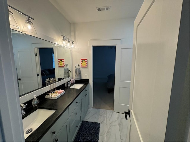 ensuite bathroom with marble finish floor, a sink, visible vents, and connected bathroom