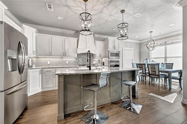 kitchen with appliances with stainless steel finishes, white cabinetry, visible vents, and a notable chandelier