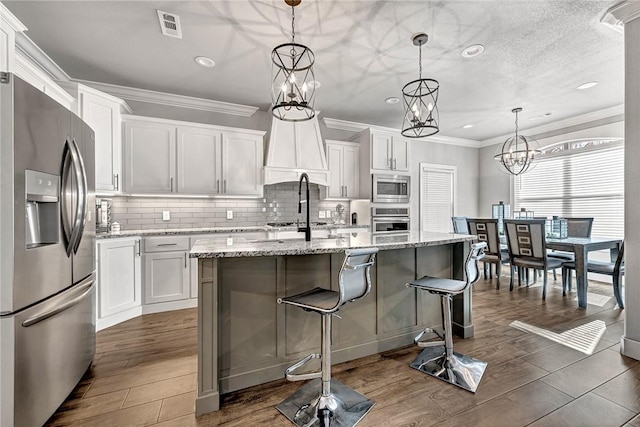 kitchen with tasteful backsplash, white cabinetry, stainless steel appliances, and ornamental molding