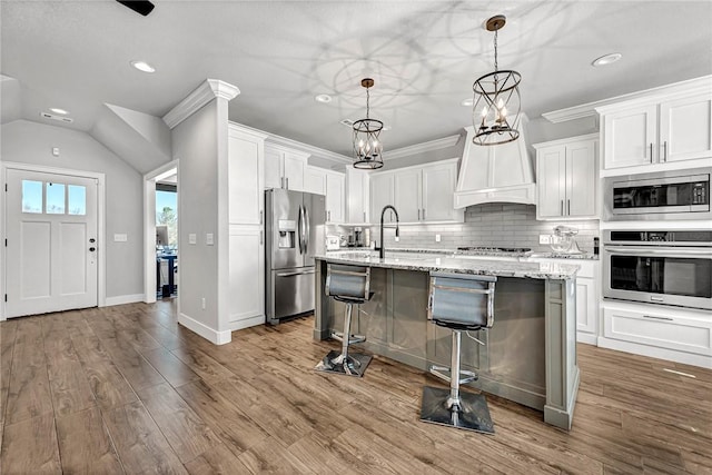 kitchen featuring backsplash, appliances with stainless steel finishes, white cabinetry, a sink, and wood finished floors