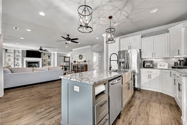 kitchen featuring wood finished floors, visible vents, white cabinets, appliances with stainless steel finishes, and crown molding