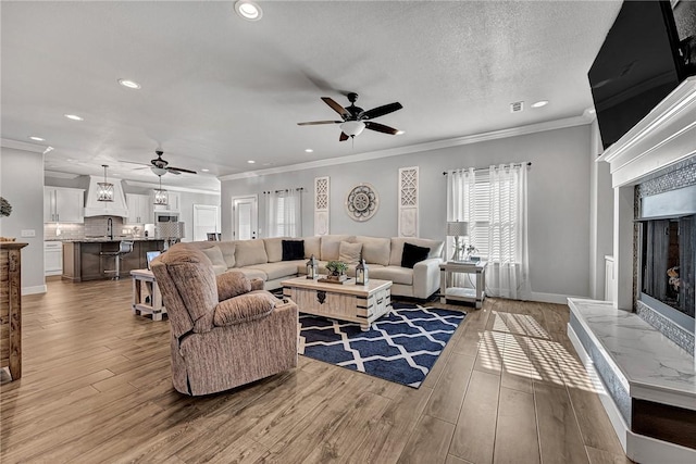 living room with light wood-style flooring, ornamental molding, and a tiled fireplace