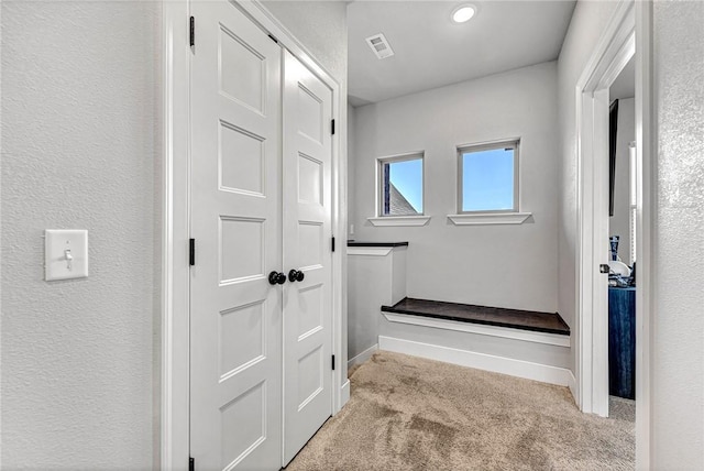 corridor with baseboards, visible vents, and carpet