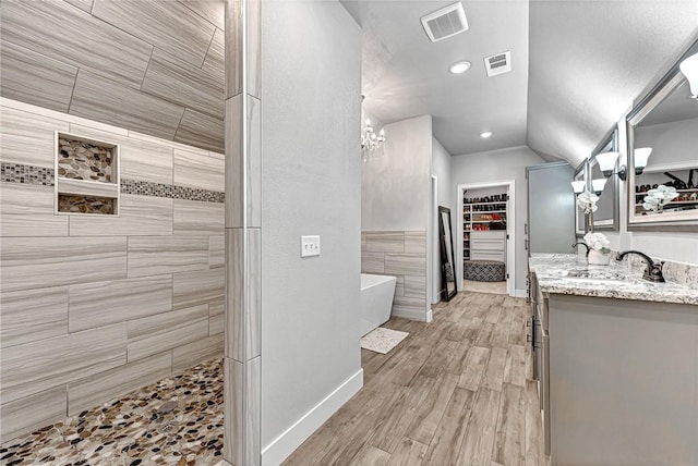 full bathroom featuring wood finished floors, visible vents, vanity, a walk in shower, and a freestanding tub