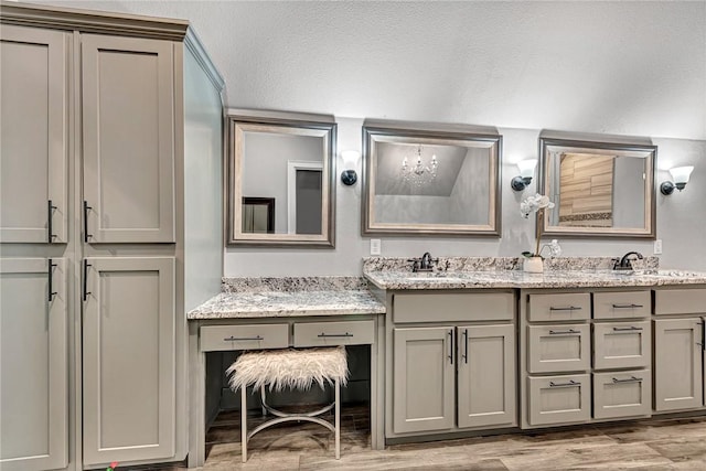 bathroom featuring double vanity, a textured ceiling, a sink, and wood finished floors