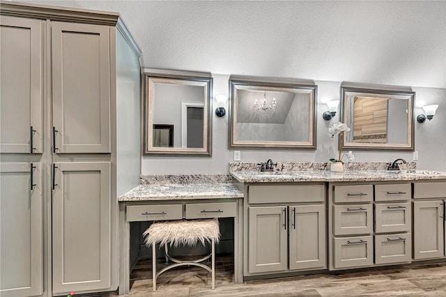 bathroom with double vanity, a sink, a chandelier, and wood finished floors