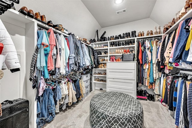 walk in closet with visible vents, carpet floors, and lofted ceiling