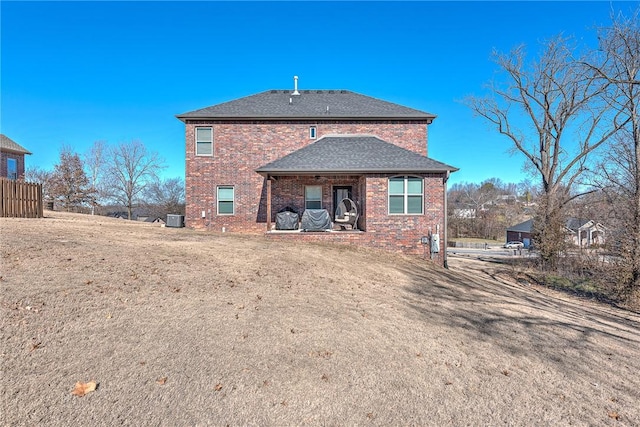 back of property featuring brick siding, a shingled roof, and central air condition unit