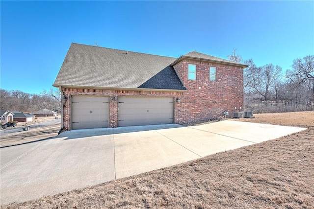 view of property exterior featuring brick siding, driveway, central AC, roof with shingles, and an attached garage