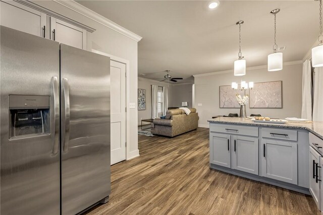 kitchen with light stone counters, gray cabinets, dark wood-style floors, stainless steel fridge, and crown molding