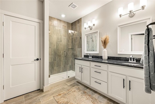 bathroom featuring double vanity, a stall shower, a sink, and visible vents