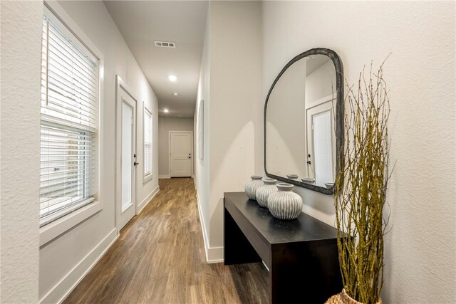 hallway featuring baseboards, visible vents, and wood finished floors