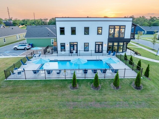 pool at dusk featuring a fenced in pool, a yard, fence, and a patio