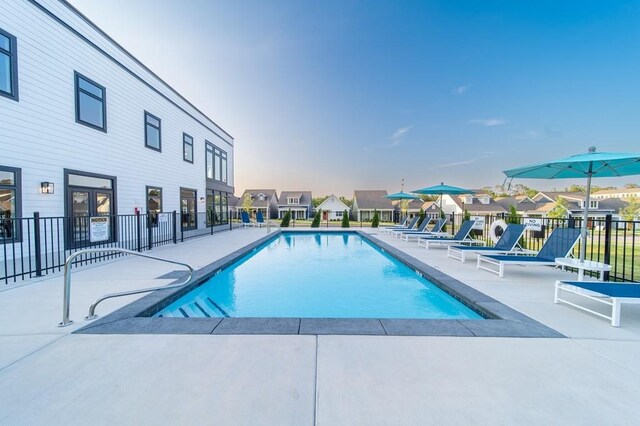 pool with a patio area and fence