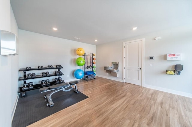 exercise area with recessed lighting, wood finished floors, and baseboards