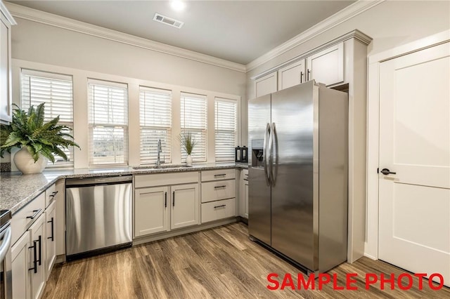 kitchen featuring visible vents, dark wood finished floors, stainless steel appliances, crown molding, and a sink