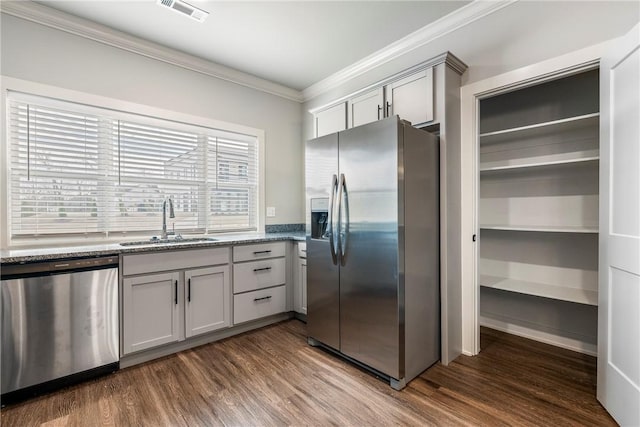 kitchen featuring light stone counters, a sink, visible vents, ornamental molding, and appliances with stainless steel finishes