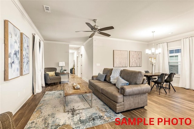 living room with visible vents, ornamental molding, wood finished floors, baseboards, and ceiling fan with notable chandelier