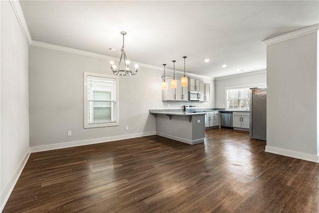 kitchen with dark wood-style floors, stainless steel appliances, a kitchen bar, a peninsula, and baseboards