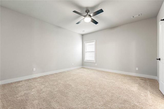 carpeted spare room featuring baseboards, visible vents, and a ceiling fan