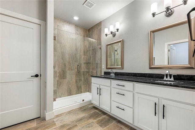 bathroom with double vanity, a sink, visible vents, and a shower stall