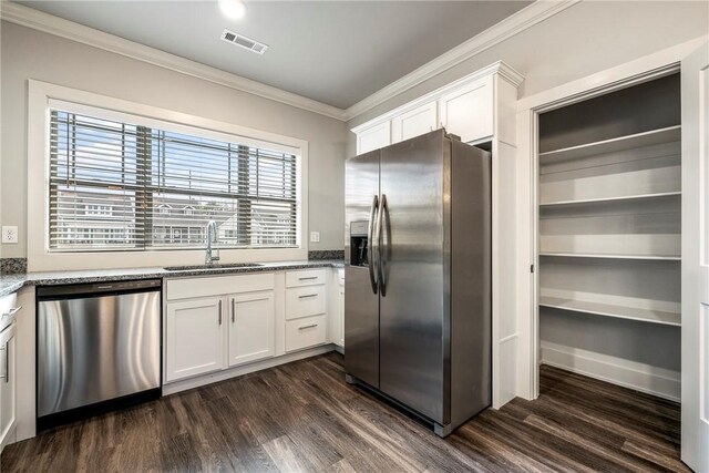 kitchen with visible vents, a sink, stainless steel appliances, crown molding, and light stone countertops